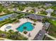 Aerial view of community pool area with tables, chairs, covered seating and tennis courts nearby at 12327 Halfmoon Lake Ter, Bradenton, FL 34211