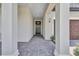 Inviting covered front porch showcasing a brick floor and a stylish front door with elegant pillars and lighting at 12743 Tahitian Pearl Cir, Parrish, FL 34219