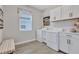 Laundry room features front loading washer and dryer, white cabinets, and a window at 12743 Tahitian Pearl Cir, Parrish, FL 34219