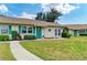 Inviting single-story home with a vibrant green front door, manicured landscaping, and a stone walkway at 1906 Canterbury Ln # 16, Sun City Center, FL 33573