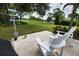 Inviting back patio with two white Adirondack chairs overlooking lush golf course and features a sign pointing to various cities at 2149 Muskogee Trl, Nokomis, FL 34275
