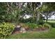 Lush landscaping featuring a stone bench, vibrant green foliage, and a variety of trees at 2149 Muskogee Trl, Nokomis, FL 34275