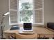 Close up view of desk with laptop in office with view of nature through bright plantation shutters at 2149 Muskogee Trl, Nokomis, FL 34275