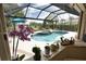 Screened-in pool area with jacuzzi, a blue patio umbrella, and lush landscaping at 2149 Muskogee Trl, Nokomis, FL 34275