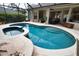 A lagoon-style pool featuring a connected hot tub and a screened-in enclosure at 2149 Muskogee Trl, Nokomis, FL 34275