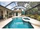 A screened pool area with a hot tub, lounge seating, and well maintained landscape at 2149 Muskogee Trl, Nokomis, FL 34275