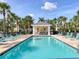 Community pool with light blue water, surrounded by lounge chairs and palm trees on a beautiful day at 262 Cape Harbour Loop # 101, Bradenton, FL 34212