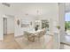 Bright dining room features modern chandelier, white table, and neutral-toned chairs with a view of the landscaped yard at 2914 Dick Wilson Dr, Sarasota, FL 34240