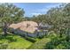 An exterior view of a beautiful home with a tile roof, screened pool, and surrounded by mature trees and lush landscaping at 2914 Dick Wilson Dr, Sarasota, FL 34240
