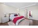 Bright main bedroom featuring a bed with red and black accents, dresser, and a doorway to the bath at 4430 Pond Brook Ct, Bradenton, FL 34211