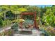 Serene backyard featuring a cozy wooden swing, lush greenery, and a variety of colorful potted plants at 4612 4Th E Ave, Bradenton, FL 34208