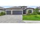 Charming home boasts a three-car garage, stone accents, tile roof, lush landscaping, and a brick paver driveway at 4971 Oyster Pearl St, Bradenton, FL 34211