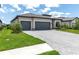 Charming home boasts a three-car garage, stone accents, tile roof, lush landscaping, and a brick paver driveway at 4971 Oyster Pearl St, Bradenton, FL 34211