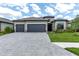 Charming home boasts a three-car garage, stone accents, tile roof, lush landscaping, and a brick paver driveway at 4971 Oyster Pearl St, Bradenton, FL 34211
