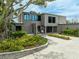 Modern gray home with ample windows, egg chairs, lush landscaping, and paver driveway at 512 Treasure Boat Way, Sarasota, FL 34242