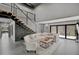 Open-concept living room features sleek tile flooring, a comfortable neutral sectional, and modern stairwell at 512 Treasure Boat Way, Sarasota, FL 34242
