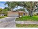 Inviting single-story home with a two car garage, lush green lawn, and mature trees providing shade at 5823 Helen Way, Sarasota, FL 34243