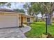 Close-up of a cozy single-story home with an attached garage, featuring a well-kept lawn and lovely landscaping at 5823 Helen Way, Sarasota, FL 34243