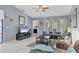 Open-concept living room with large windows, comfortable seating, and a ceiling fan, filled with natural light at 5823 Helen Way, Sarasota, FL 34243