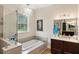 Bright bathroom featuring a soaking tub, glass-enclosed shower, and dual vanity with elegant fixtures at 601 Suffolk Cir, Nokomis, FL 34275