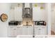 Close up of kitchen with white cabinets, designer backsplash and stainless steel range hood at 601 Suffolk Cir, Nokomis, FL 34275