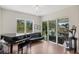 Living area with large windows, piano, black sofa and chandelier at 601 Suffolk Cir, Nokomis, FL 34275