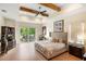 Bright main bedroom with wood-look floors, tray ceiling with beams, and access to the patio at 601 Suffolk Cir, Nokomis, FL 34275