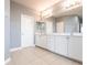 Light bathroom featuring a double sink vanity with marble countertop, a large mirror and neutral tile floor at 7113 Park Tree Dr, Tampa, FL 33625