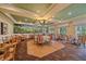 Elegant dining area featuring a tropical mural, comfortable seating, and views of the surrounding landscaping at 7507 Ascot Ct, University Park, FL 34201