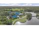 Scenic aerial view of a community clubhouse, lake, and golf course surrounded by lush greenery at 7507 Ascot Ct, University Park, FL 34201