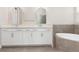 Spacious bathroom with double vanity sinks, tiled floors, and a soaking tub with tiled surround at 7508 Ripetta St, Sarasota, FL 34240
