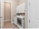 A laundry room with white washer and dryer, white cabinets and a view into the adjacent room at 7508 Ripetta St, Sarasota, FL 34240