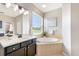 Bathroom featuring a double vanity sink and a large soaking tub by a bright window at 8640 Stone Harbour Loop, Bradenton, FL 34212