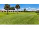 Well-manicured golf course with palm trees under a clear blue sky, surrounded by community buildings at 8640 Stone Harbour Loop, Bradenton, FL 34212