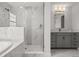 Bright bathroom featuring a glass-enclosed shower, soaking tub, and gray vanity at 8932 Isabella Cir, Parrish, FL 34219