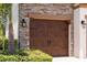 A close-up of a beautiful wood-look garage door with stone surround and decorative hardware, framed by lush landscaping at 8932 Isabella Cir, Parrish, FL 34219