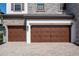 A wide driveway leads to beautiful wood-look three-car garage doors with stone accents and exterior lighting at 8932 Isabella Cir, Parrish, FL 34219