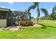 Backyard paradise featuring a screened-in pool, lush landscaping, and tropical palm trees at 9229 52Nd E Ave, Palmetto, FL 34221