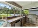 Outdoor kitchen with a stainless steel gas grill, sink and mini-fridge with bar seating and a view of the pool at 9229 52Nd E Ave, Palmetto, FL 34221