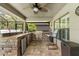Outdoor kitchen with stainless steel appliances, stone counter, a ceiling fan, and an adjacent lounge area at 9229 52Nd E Ave, Palmetto, FL 34221