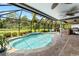 Screened pool with water feature, outdoor kitchen, ceiling fans, stone counters, tile pavers, and a view of the greenery beyond at 9229 52Nd E Ave, Palmetto, FL 34221