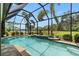 A picturesque view of the screened-in pool area featuring a lush green lawn and waterfront scenery at 9229 52Nd E Ave, Palmetto, FL 34221