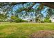 Expansive green backyard features lush lawn, mature trees, and a screened in porch, ideal for outdoor entertaining at 928 Pineland Ave, Venice, FL 34285