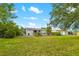 The home's exterior and the lush green backyard filled with various plants and trees at 928 Pineland Ave, Venice, FL 34285
