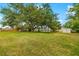 Large, well-maintained backyard with ample green space, mature shade trees, and privacy fencing, perfect for outdoor activities at 928 Pineland Ave, Venice, FL 34285
