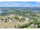 Expansive aerial view of a rural property with multiple buildings, paddocks, and a tranquil lake in the distance at 12714 Tyler Run Ave, Odessa, FL 33556
