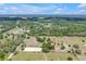 Sweeping aerial view showcasing fenced pastures, an equestrian ring, and lush greenery on the ranch at 12714 Tyler Run Ave, Odessa, FL 33556