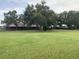Spacious green lawn leads up to horse stables featuring a charming red roof and dark wood at 12714 Tyler Run Ave, Odessa, FL 33556