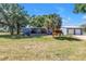 Quaint single-story home with a manicured lawn, mature trees, detached garage, and charming front porch at 12714 Tyler Run Ave, Odessa, FL 33556