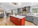 Bright, open kitchen features gray cabinets, stainless appliances, stone backsplash, and red island with white countertop at 12714 Tyler Run Ave, Odessa, FL 33556